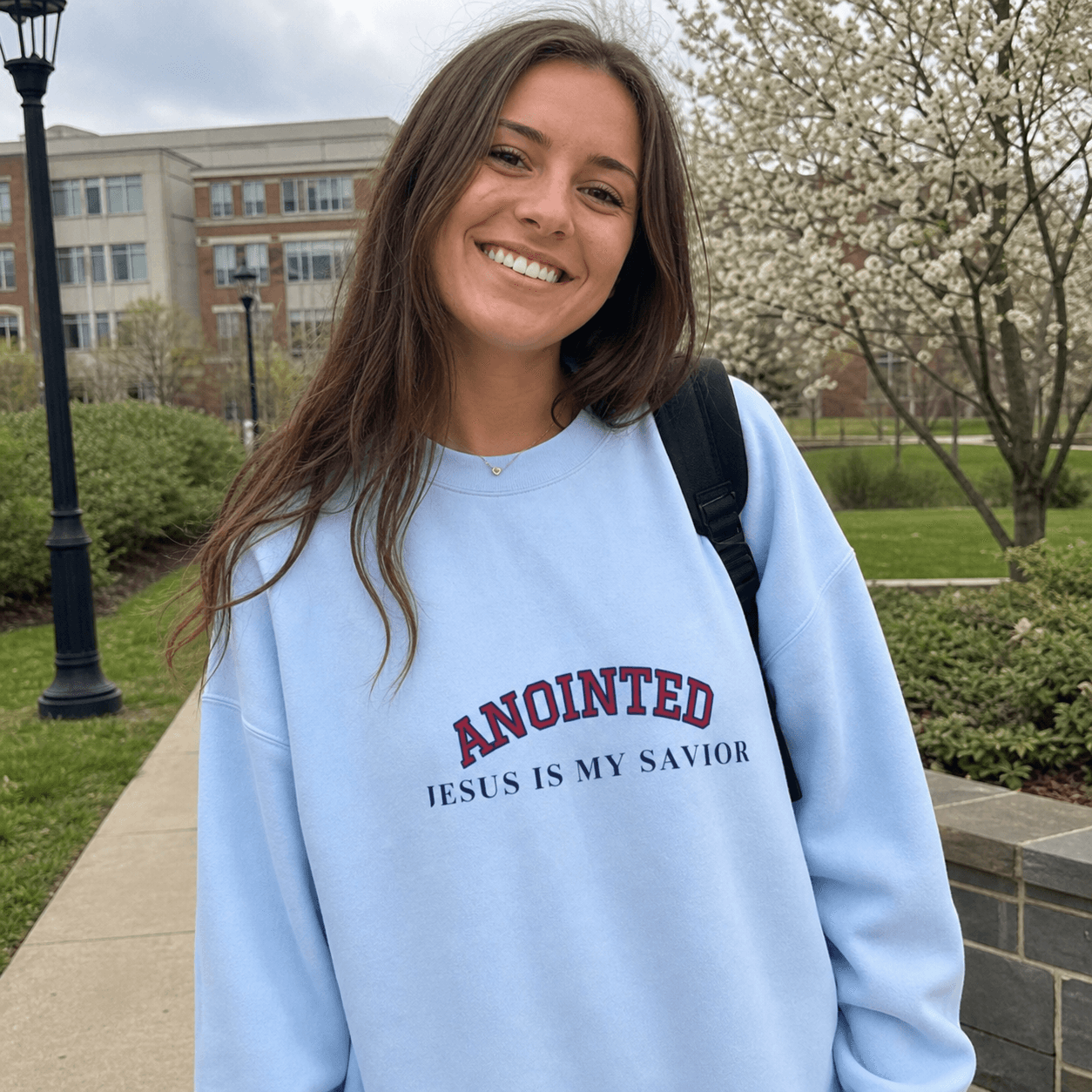 Customer wearing the light blue My Jesus sweatshirt outdoors on campus